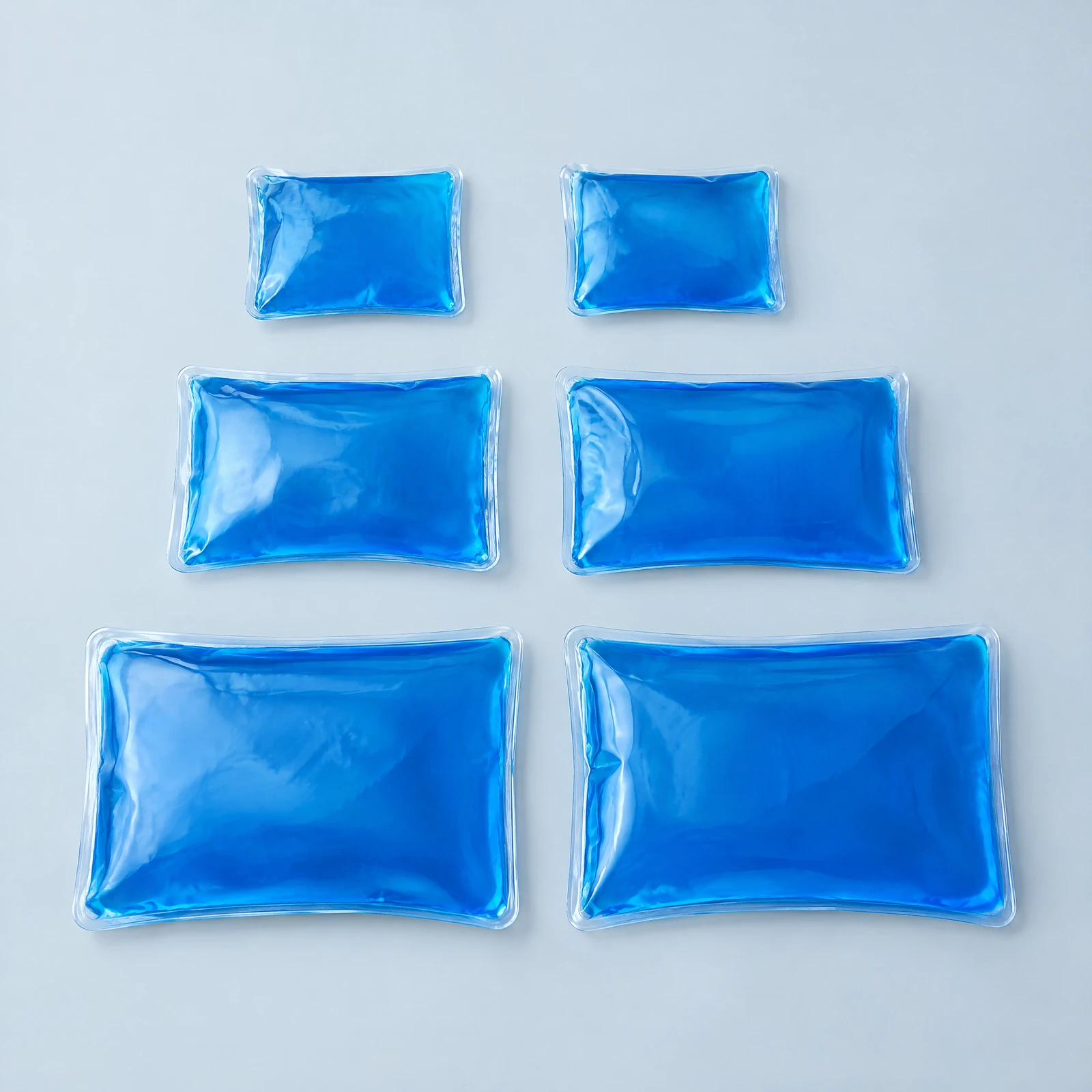 Six blue hot/cold packs in three sizes arranged in rows on a light surface