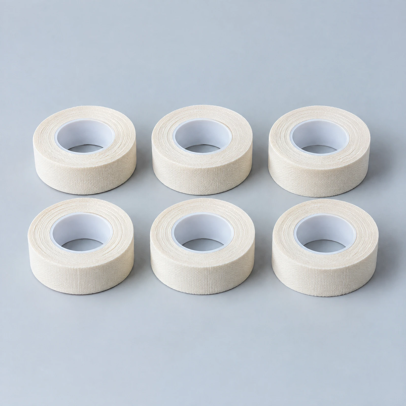 Six rolls of cream tape on white cores arranged in two rows