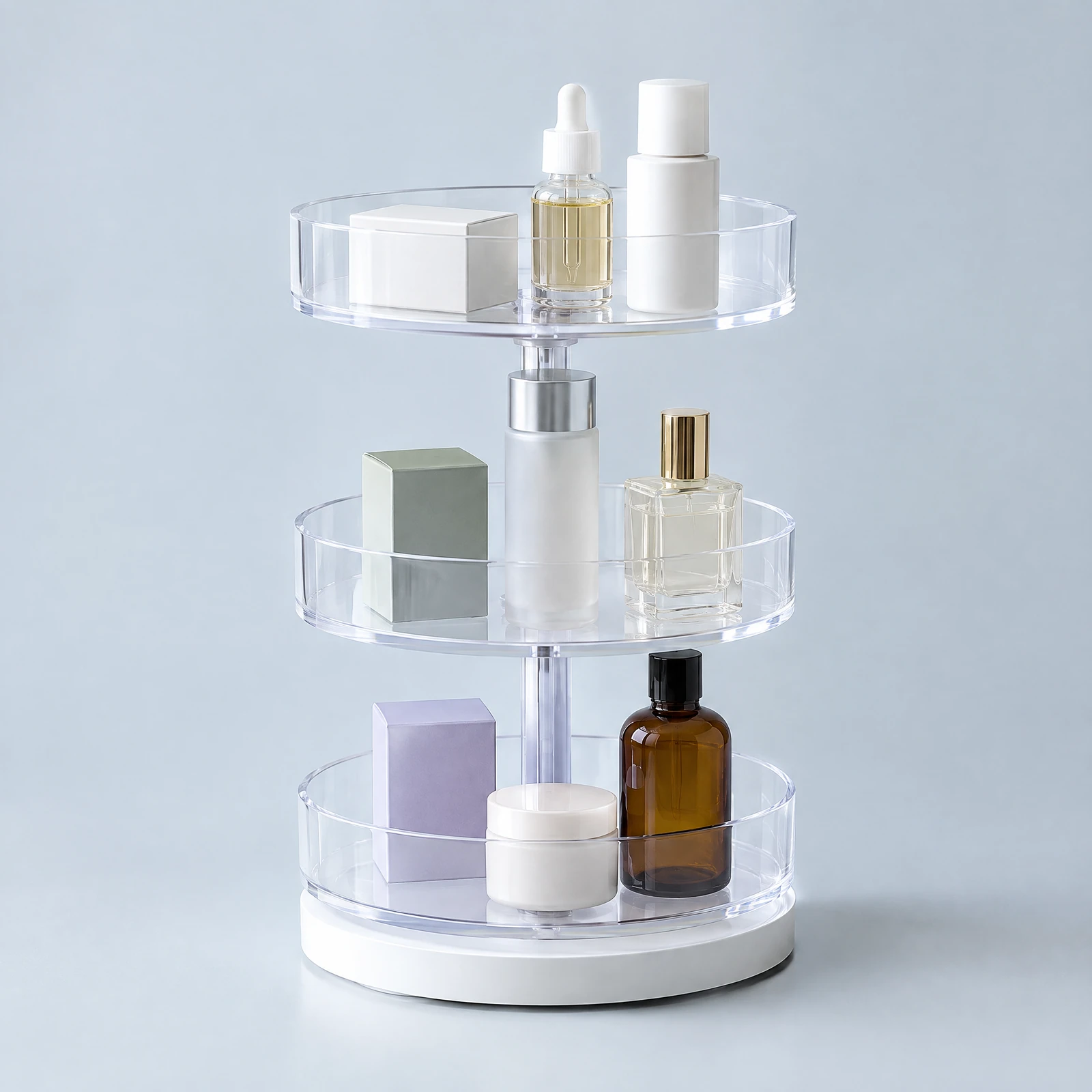 Three-tier clear rotating organizer on a white base holding small boxes and bottles